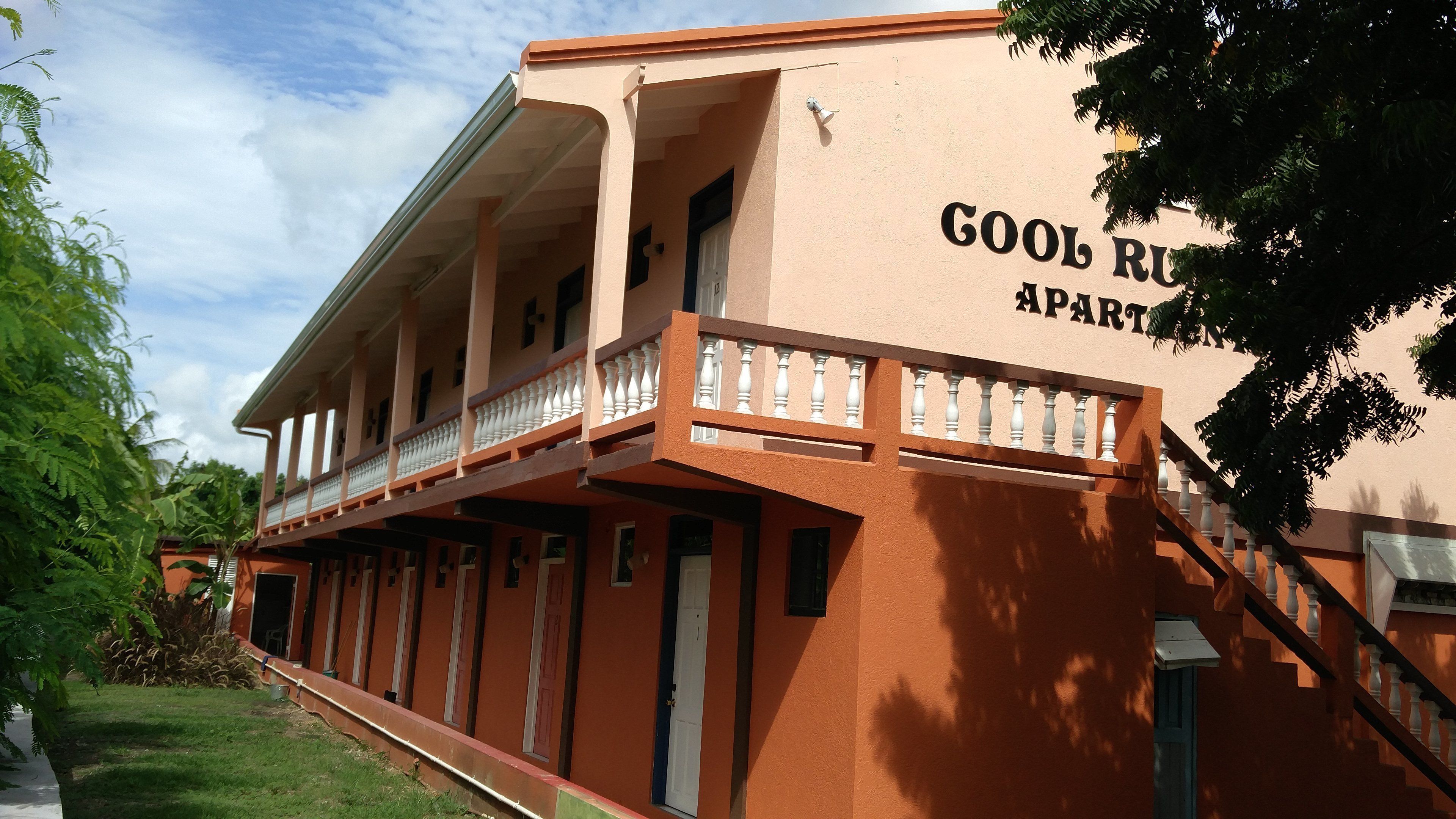A building with a sign reading "GOOL RUPA PART". It has a balcony with white balustrades and a staircase leading to the entrance.