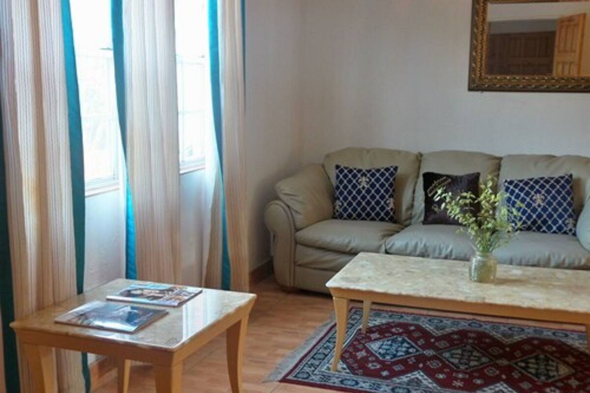 A living room with a sofa, a coffee table, a rug, and a mirror on the wall.
