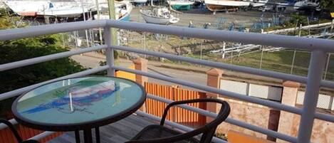 A balcony with a round table and two chairs, overlooking a marina with various boats.