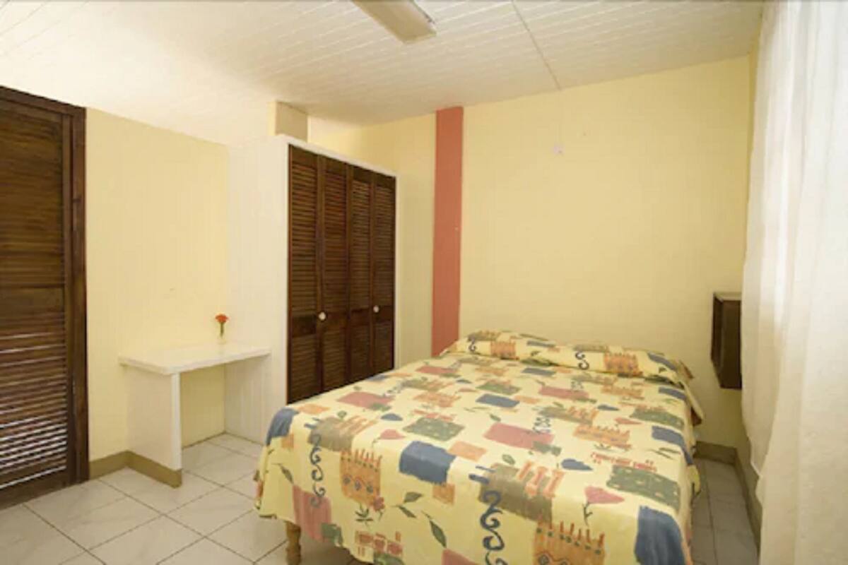 A bedroom with a bed, a small desk, and a wardrobe.