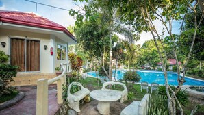 A house with a red roof, a swimming pool, and outdoor seating.
