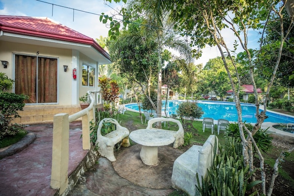 A house with a red roof, a swimming pool, and outdoor seating.