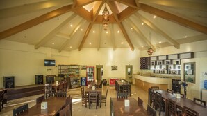 A spacious restaurant with high ceilings, wooden beams, and a central bar area.