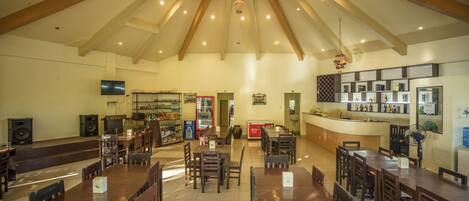 A spacious restaurant with high ceilings, wooden beams, and a central bar area.
