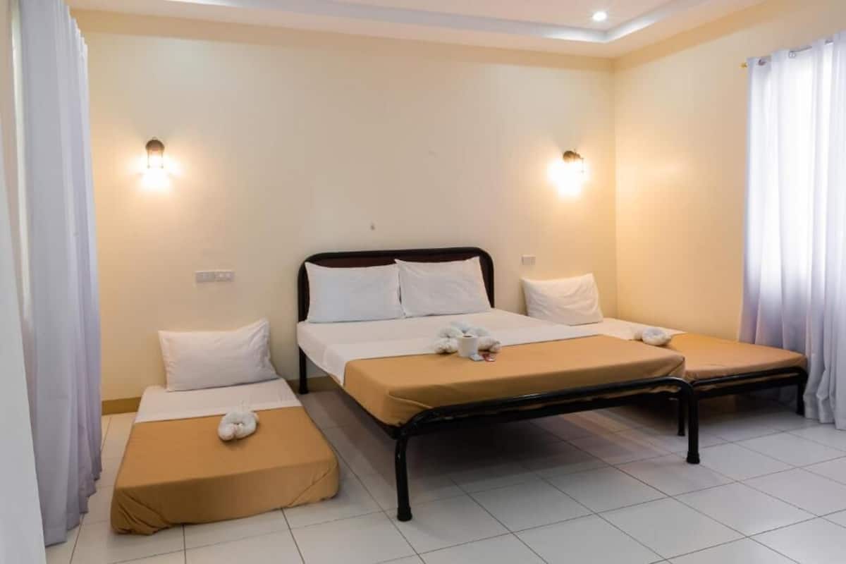 A hotel room with two single beds, a small table, and two wall-mounted lights.
