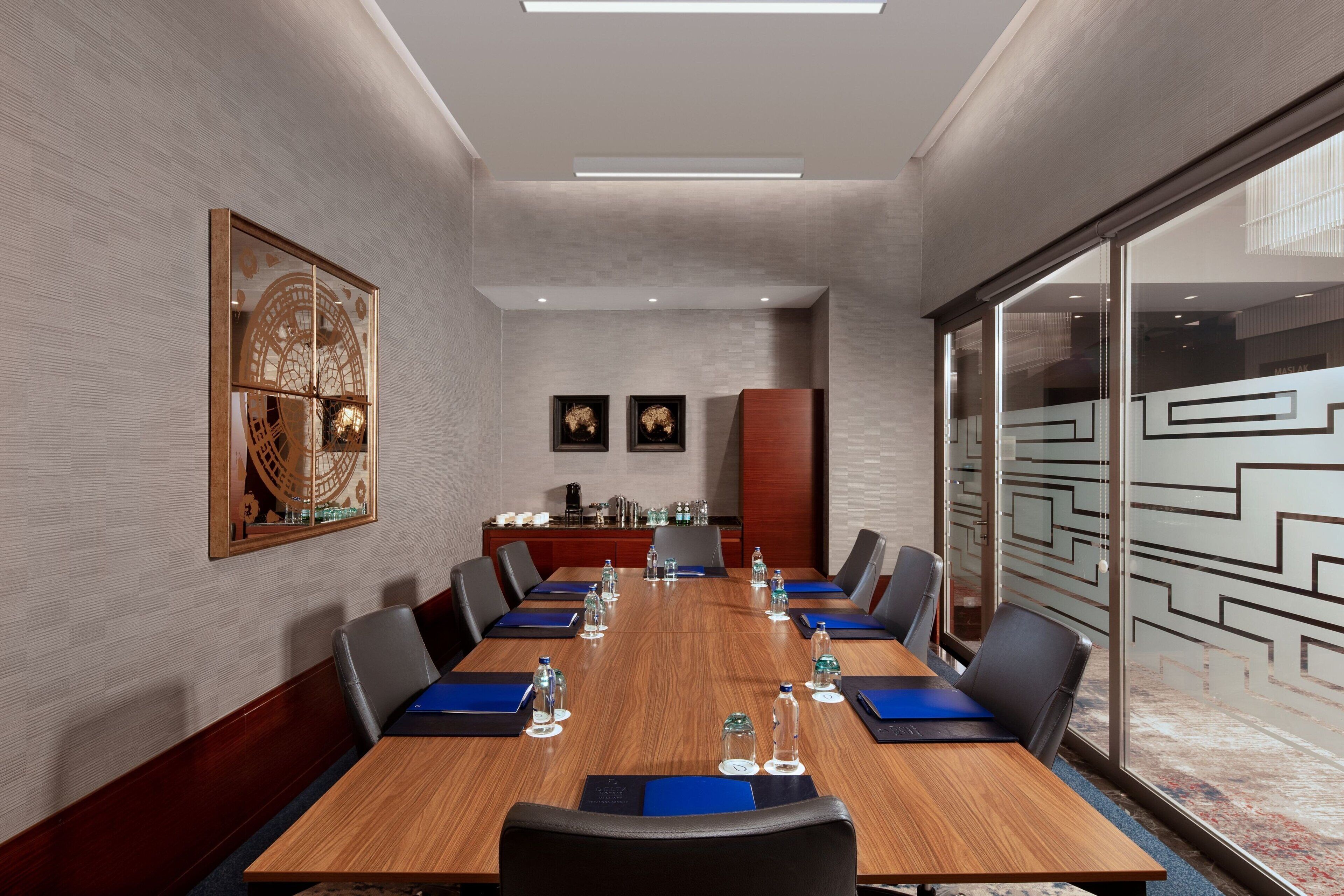 A conference room with a long table, chairs, water bottles, and a coffee station.