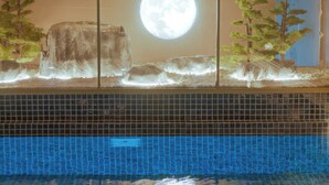 A swimming pool with a tiled floor and a view of a moonlit landscape through a glass partition. - Delta Hotels By Marriott Istanbul Levent (Istanbul)