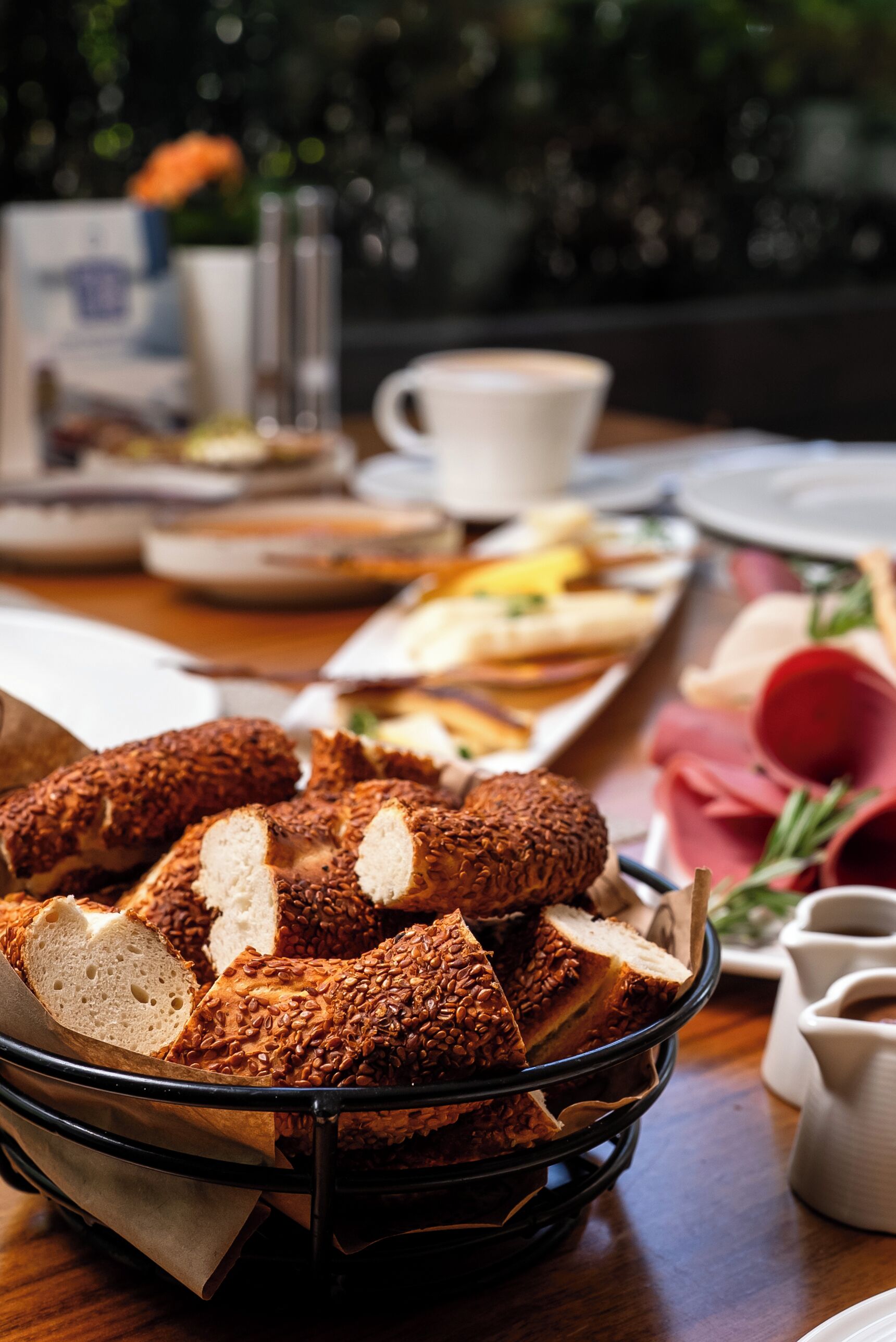 A breakfast setting with a variety of bread, pastries, and a coffee cup on a table.