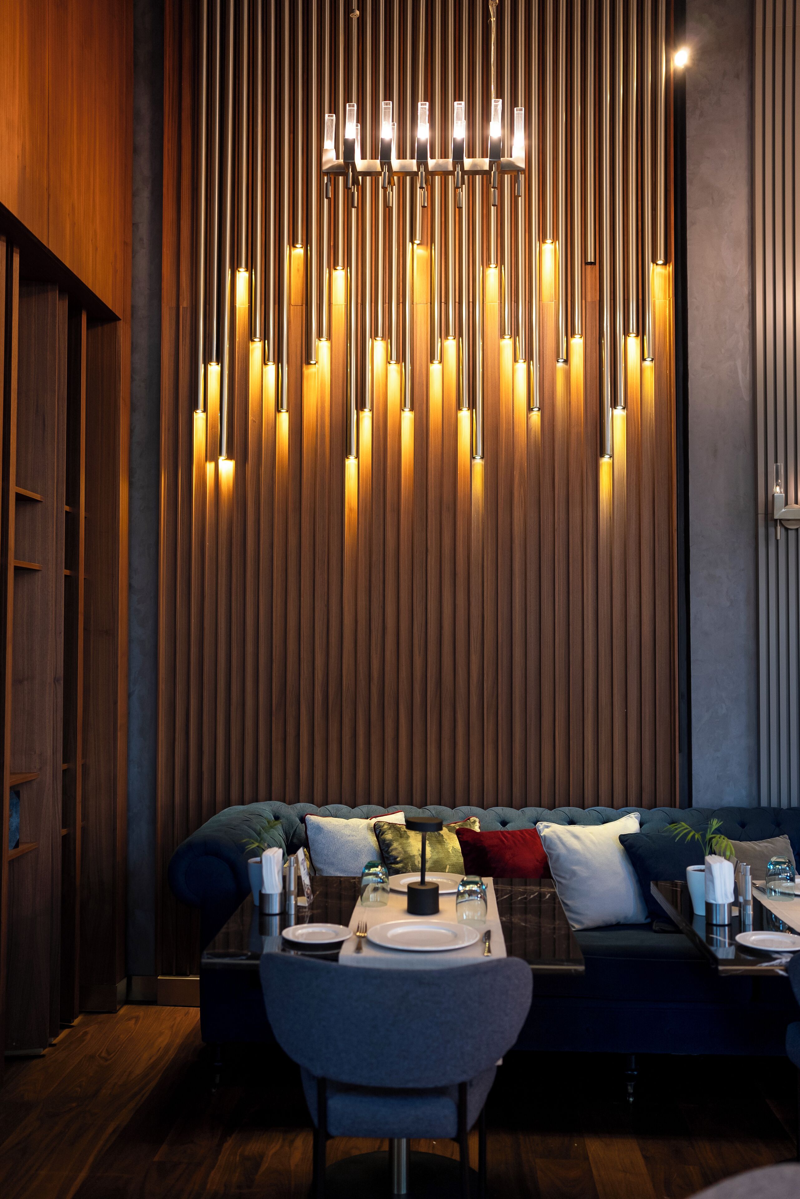 A modern dining area with a wooden wall, a chandelier, and a sofa set.