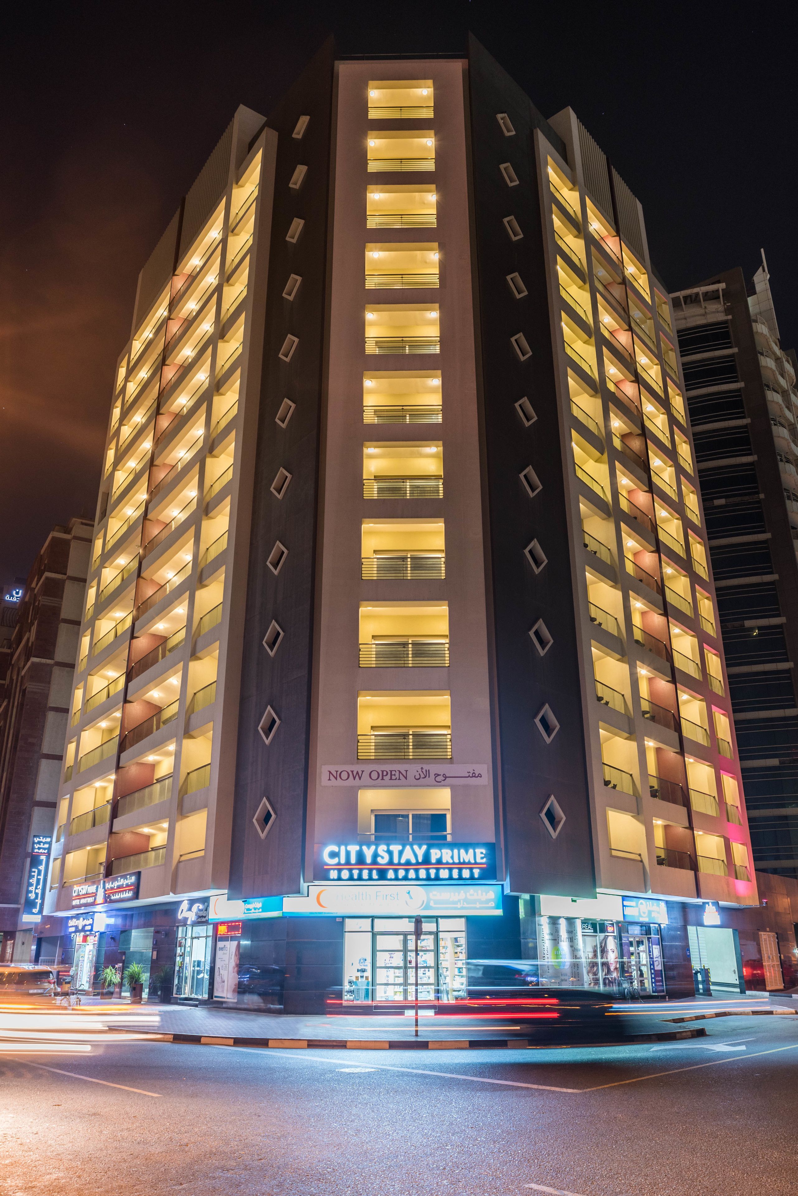 A multi-story hotel with illuminated windows and a sign indicating it is now open.