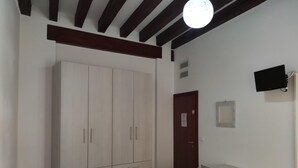 A bedroom with a large wardrobe, a desk with a chair, a bed, and a television mounted on the wall. - Sweet Venice - rooms & apartments (Venice)