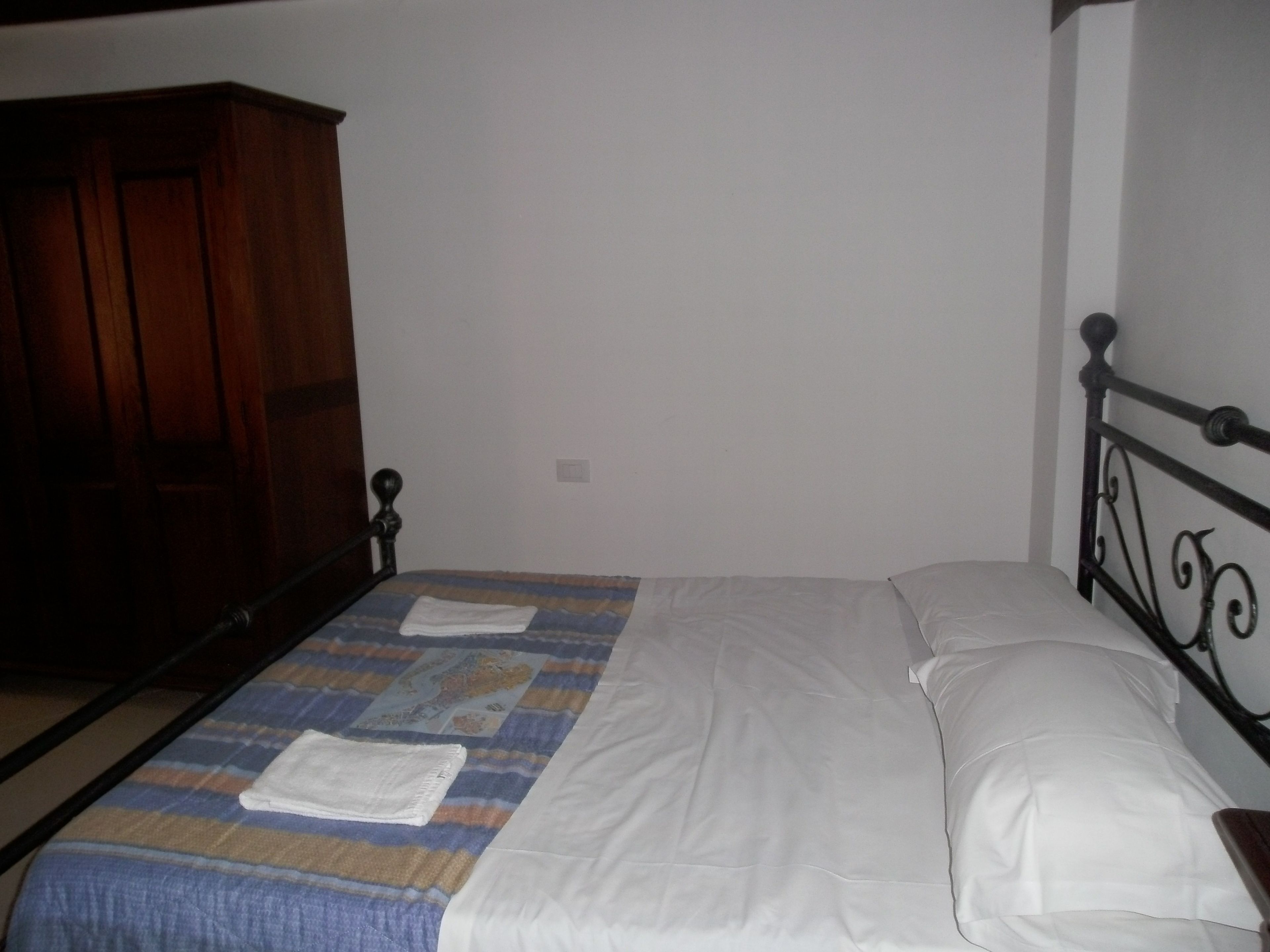 Une chambre à coucher avec un lit, une armoire en bois et un mur blanc.