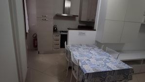 A compact kitchen with white cabinets, a gas stove, and a stainless steel range hood. - Sweet Venice - rooms & apartments (Venice)