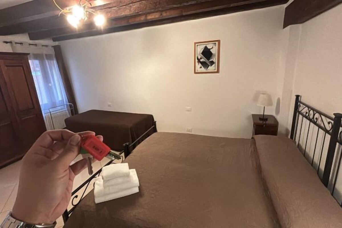 Ett hotellrum med en säng, ett nattduksbord, en lampa och ett fönster med gardiner.
