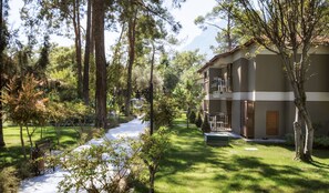 A building with a balcony, surrounded by trees and a pathway.