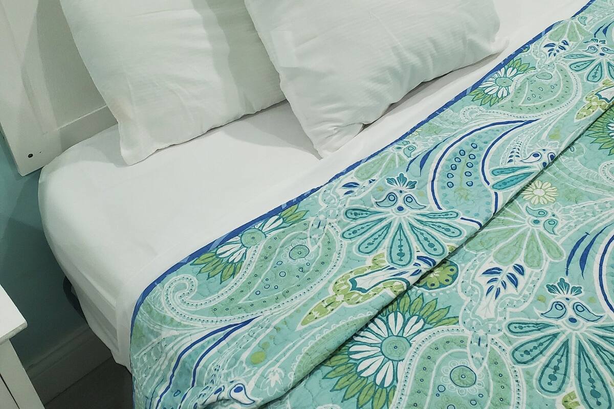 Un letto con biancheria bianca e una coperta a motivi.