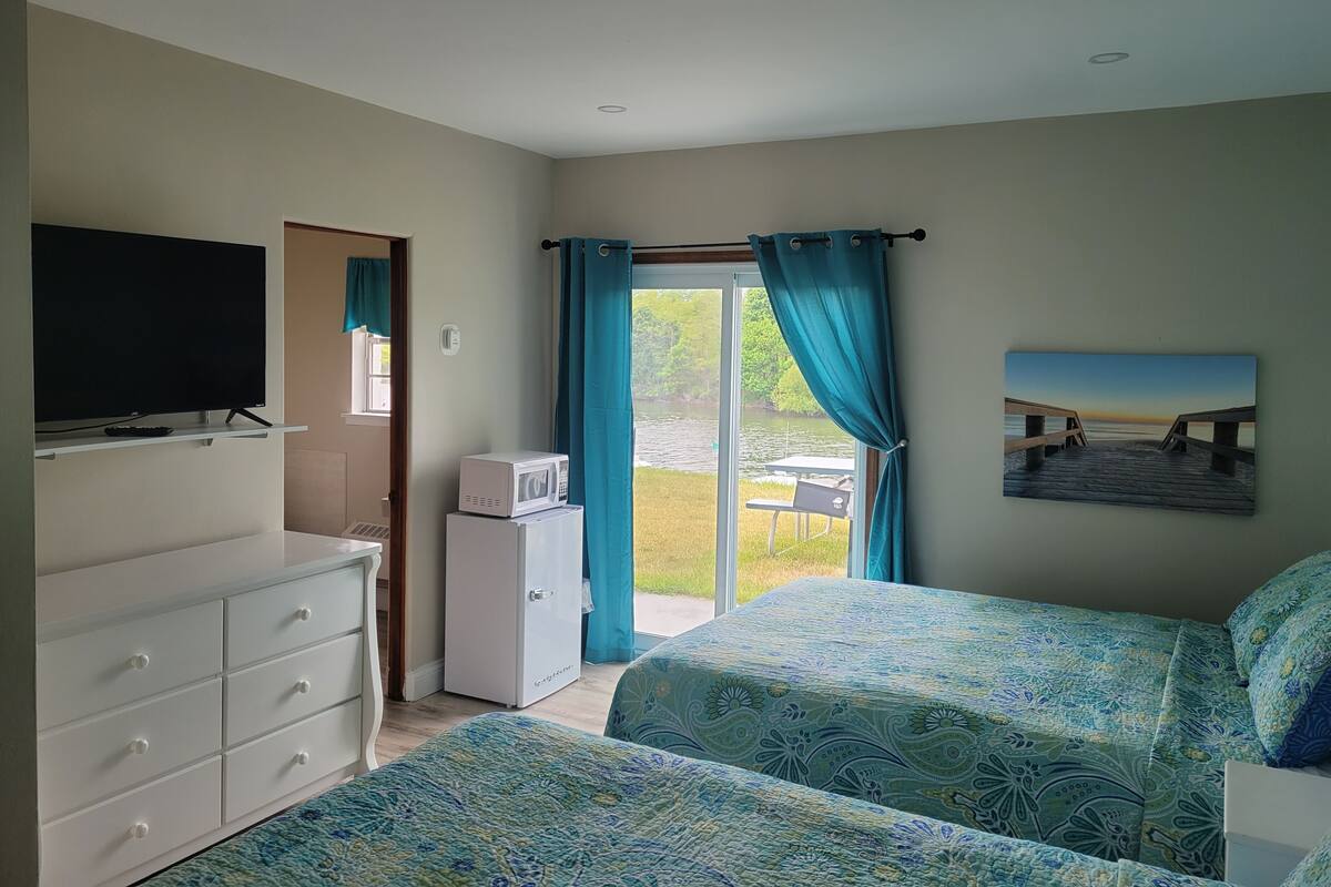 Camera da letto con due letti, una TV, un forno a microonde e vista su un molo e l'acqua.
