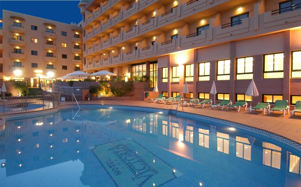 A hotel with a swimming pool, multiple balconies, and outdoor seating areas.