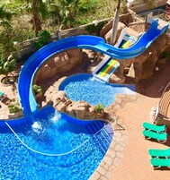 Una piscina al aire libre, sombrillas, sillones reclinables de piscina