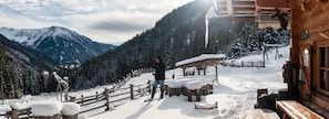 A wooden cabin with a snow-covered deck, a wooden fence, and a mountain view in the background. - La Casies Mountain Living Hotel (Valle di Casies)