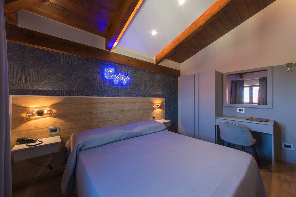 A modern bedroom with a bed, bedside table, and desk.