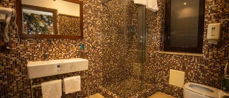 A bathroom with mosaic tile walls, a glass-enclosed shower, a sink with a mirror, and a toilet.