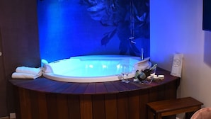 A spa area with a hot tub, wooden flooring, and a seating area with a table and chairs. - Hotel Vogue (Giugliano in Campania)