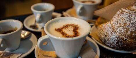 A table with a pastry, cups of coffee, and sugar packets.