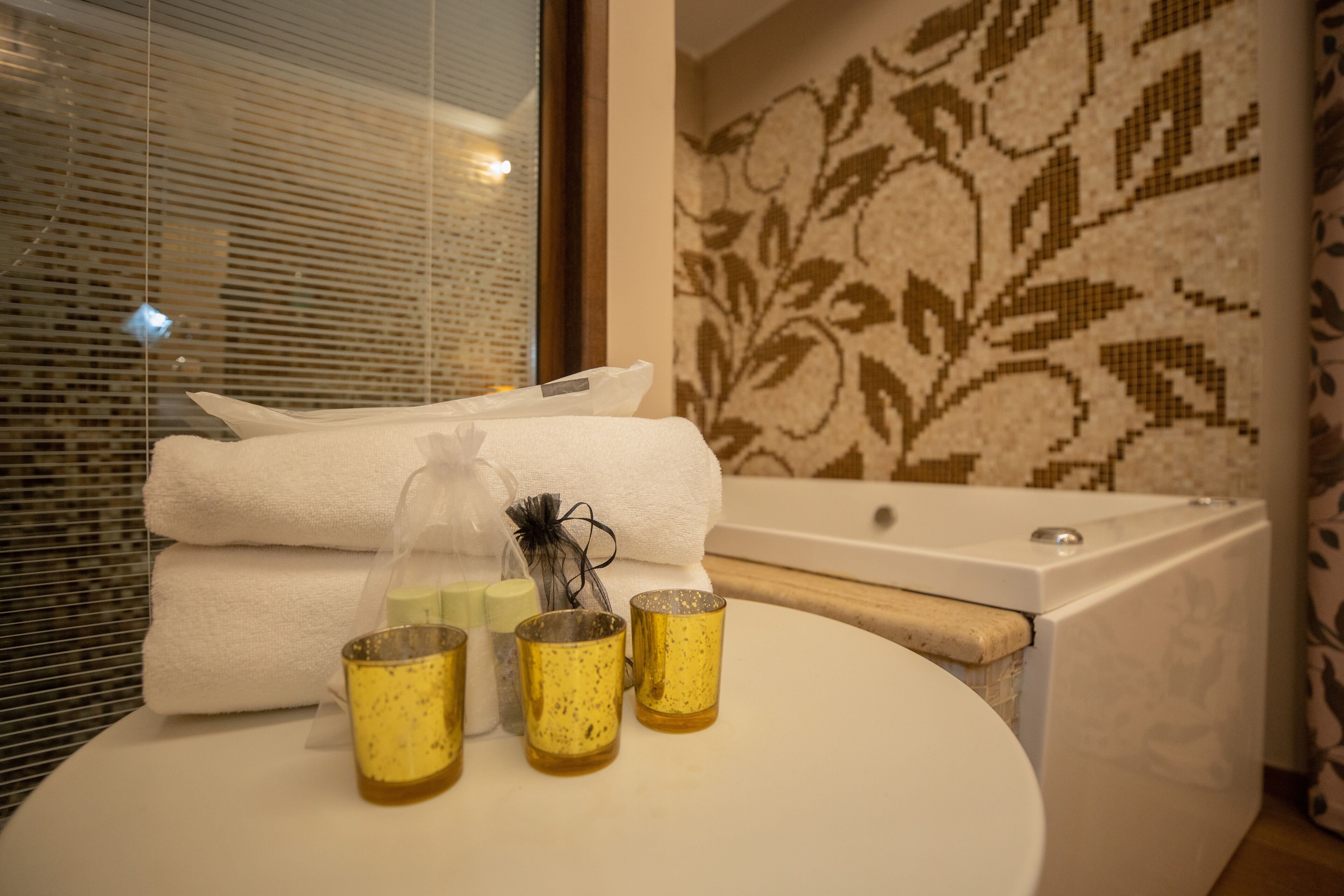 A bathroom with a white sink, three glass cups, a towel, and a bottle of soap.