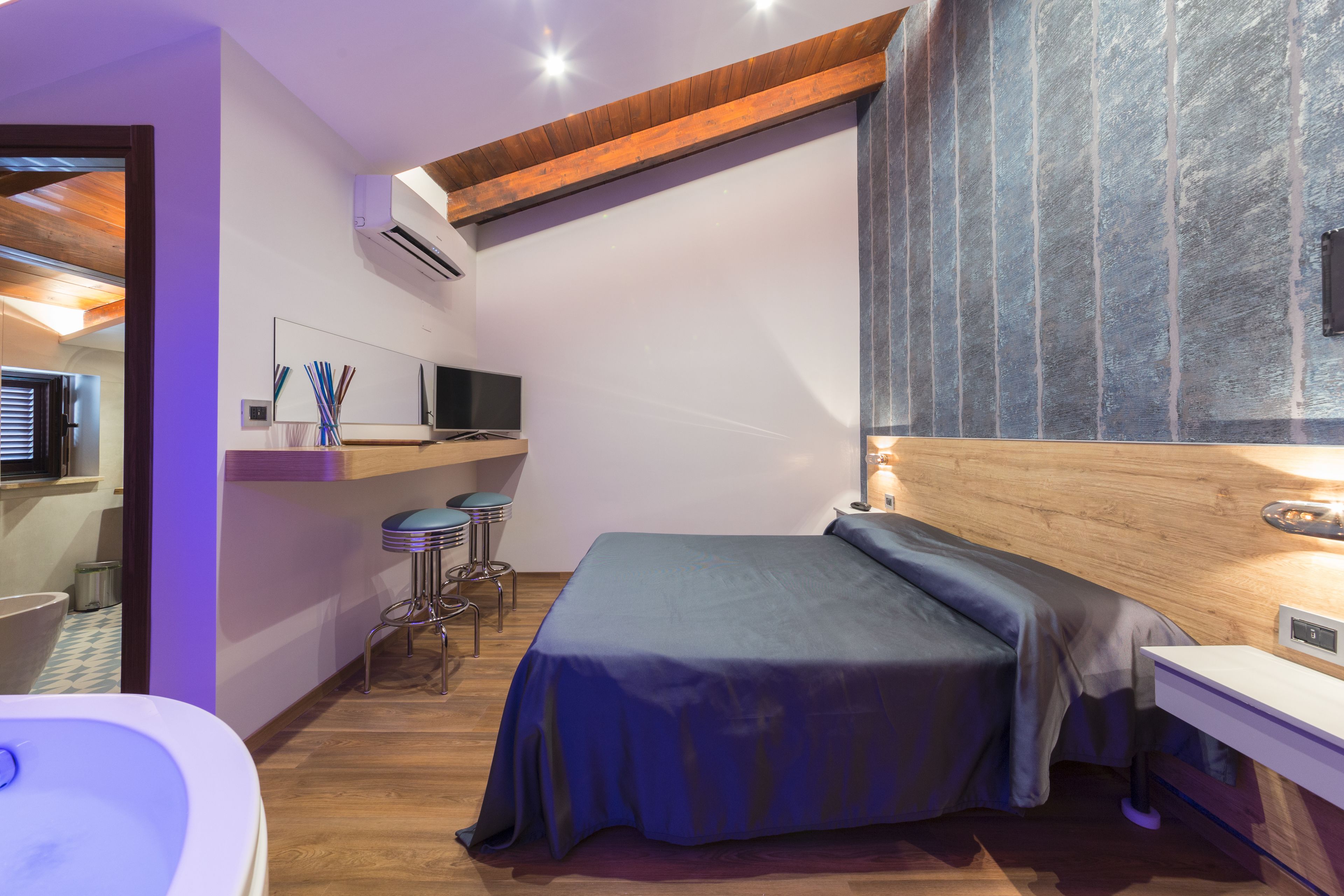 Un dormitorio moderno con cama, un escritorio pequeño, una silla y un baño con bañera.