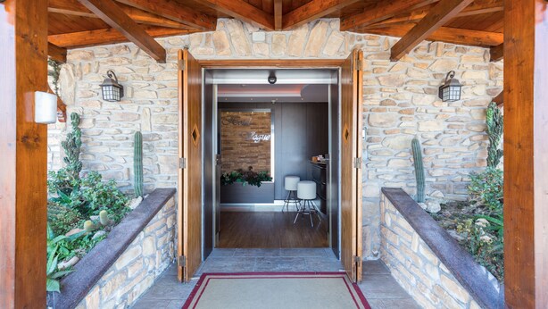 A stone-walled entrance with a wooden ceiling, a reception desk, and a seating area. - Hotel Vogue (Giugliano in Campania)
