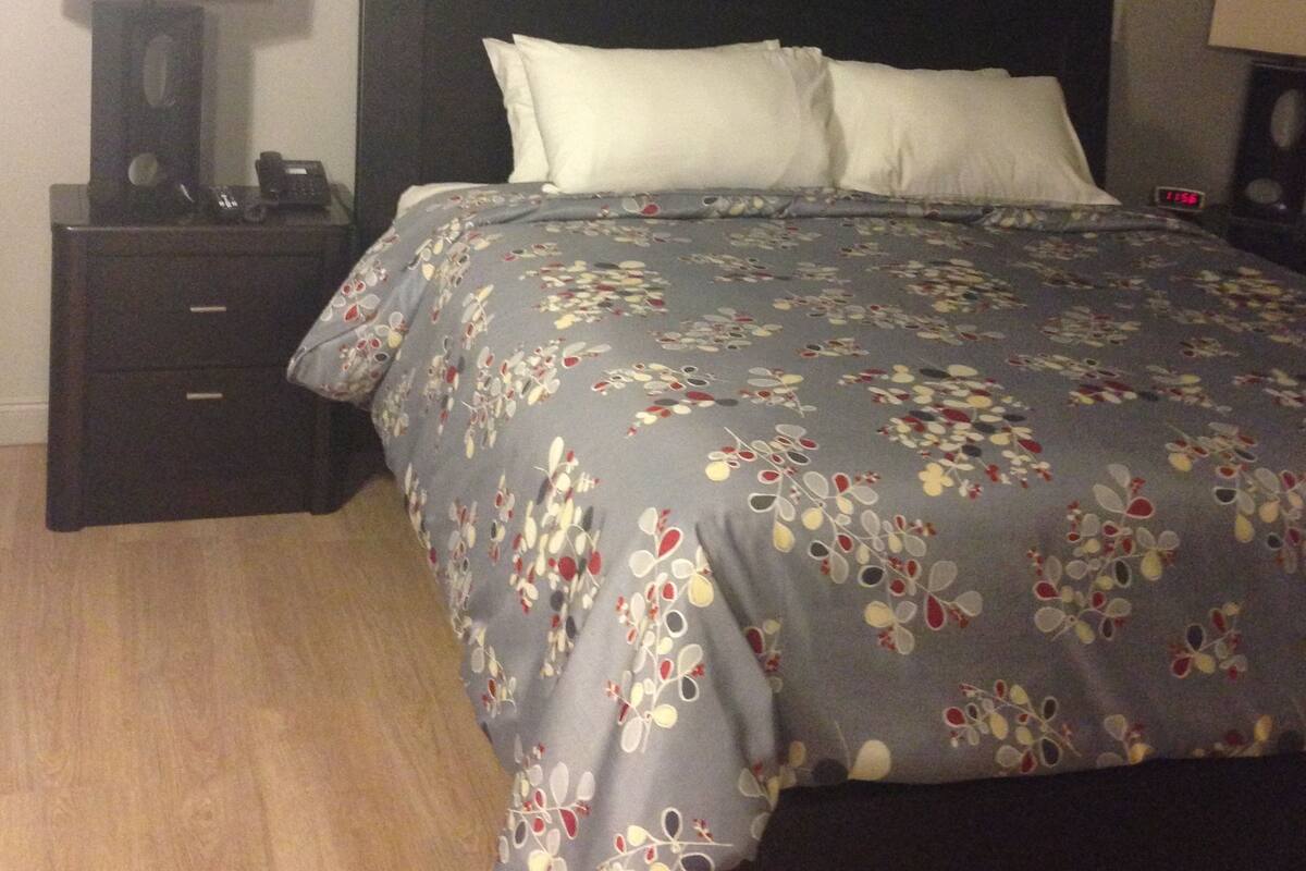 A bedroom with a bed, nightstands, a ceiling fan, and wall-mounted lamps.
