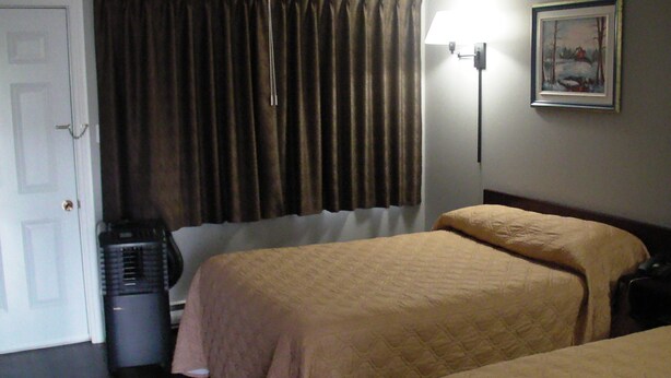 Habitación de hotel con dos camas, una puerta, un radiador y un cuadro en la pared.