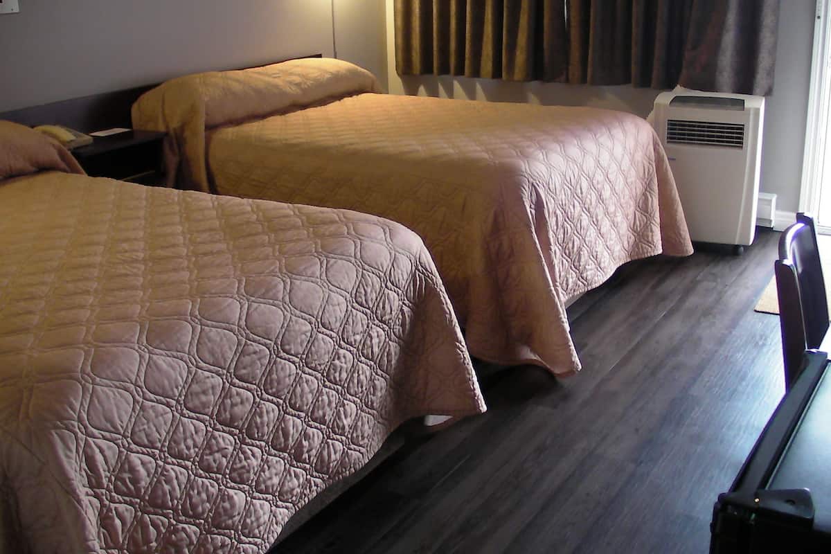 Two single beds with beige bedding in a hotel room.