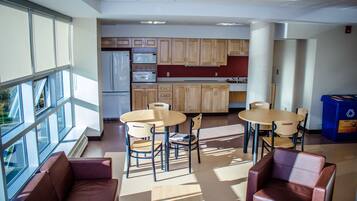 A modern kitchen with wooden cabinets, a refrigerator, microwave, and a dining area with a table and chairs.