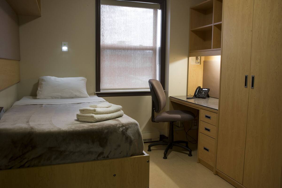 A bedroom with a bed, a desk, and a wardrobe.