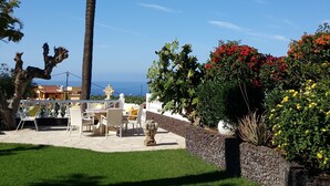 A patio area with outdoor furniture, a palm tree, and a view of the ocean. - Apartamentos Villa Rosalva (Puerto de la Cruz)