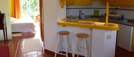 A kitchen with yellow cabinets, a coffee maker, and two stools.