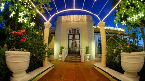 A well-lit entrance with a tiled pathway leading to a building, surrounded by potted plants and decorative lights. - Apartamentos Villa Rosalva (Puerto de la Cruz)