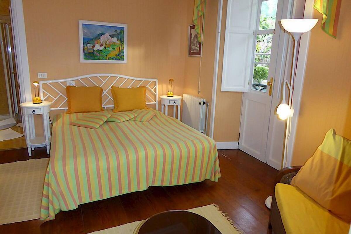 Ein Schlafzimmer mit einem Bett, zwei Nachttischen, einem Fenster und einem Bild an der Wand.