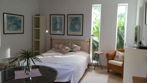 A bedroom with a bed, a bedside table, a chair, a lamp, and framed pictures on the wall. - Apartamentos Villa Rosalva (Puerto de la Cruz)