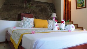 A neatly made bed with a white and yellow bedspread, decorative pillows, and a potted plant. - Romance Bungalows  (Mahé Island)