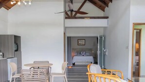 A modern interior with a dining area, a sofa, and a bed in the background. - Romance Bungalows  (Mahé Island)