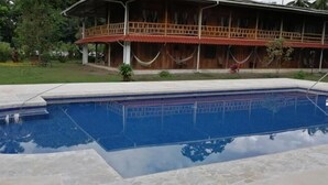 Uma piscina com uma casa de madeira ao fundo.