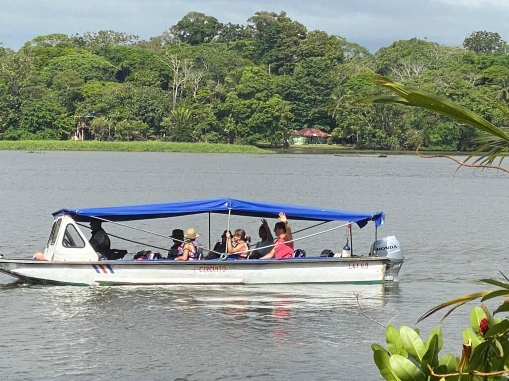 A boat with a blue canopy, passengers, and a motor.