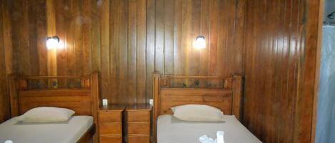 A wooden room with two beds, a ceiling fan, and wall-mounted lights.