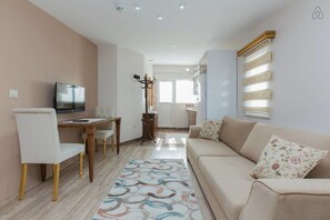 A modern living room with a sofa, a TV, and a dining area with a table and chairs.