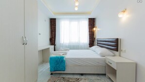 A bedroom with a bed, bedside table, wardrobe, and a window with curtains. - Taximum Suites (Istanbul)