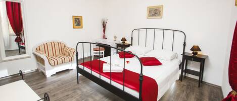 A bedroom with a bed, a chair, a desk, and a nightstand.
