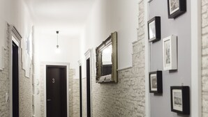 A hallway with a stone wall, framed pictures, and a door marked with the number 3. - Prior Suites Split (Split)